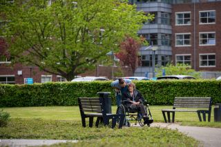 Bewoner in rolstoel wandelend met medewerker bij ZINN locatie De Dilgt
